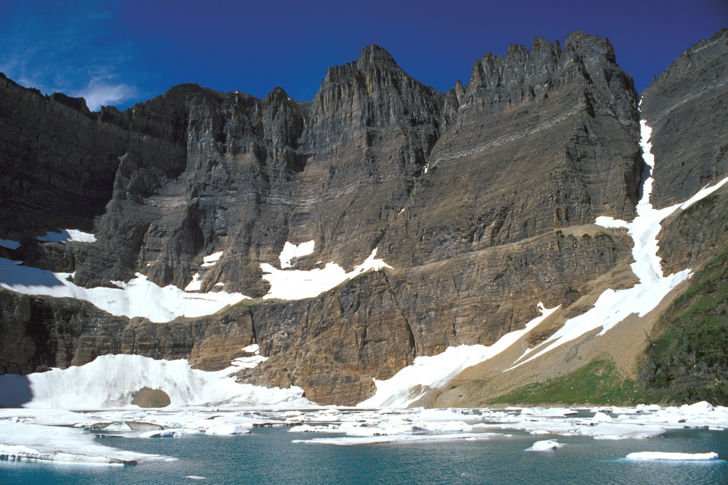 冰块漂浮的 Iceberg Lake 与环绕湖面的高耸岩壁